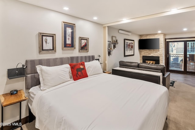 555 E Lionshead Cir Unit 207, Vail, CO 81657 - bedroom with a wall unit AC, recessed lighting, access to outside, a fireplace, and wood finished floors