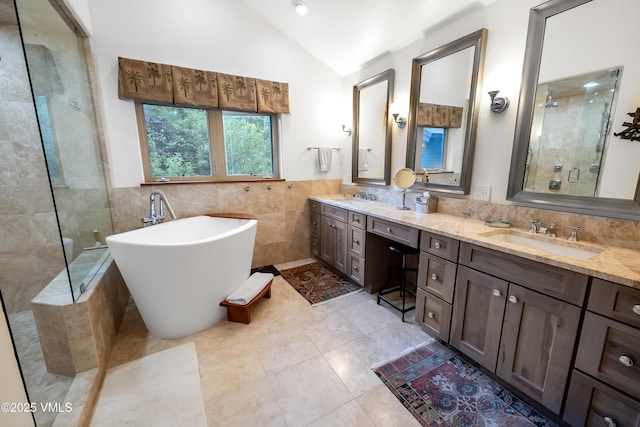2832 Kinnickinnick Rd Unit 4, Vail, CO 81657 - bathroom featuring tile walls, vaulted ceiling, a freestanding bath, a tile shower, and double vanity