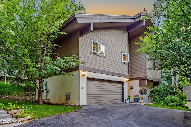2832 Kinnickinnick Rd Unit 4, Vail, CO 81657 - view of front of house with asphalt driveway, stucco siding, and an attached garage