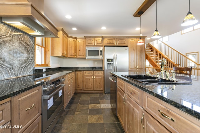 kitchen with premium range hood, sink, dark stone counters, pendant lighting, and stainless steel appliances