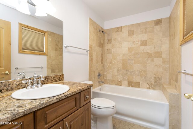 full bathroom with tiled shower / bath, vanity, and toilet