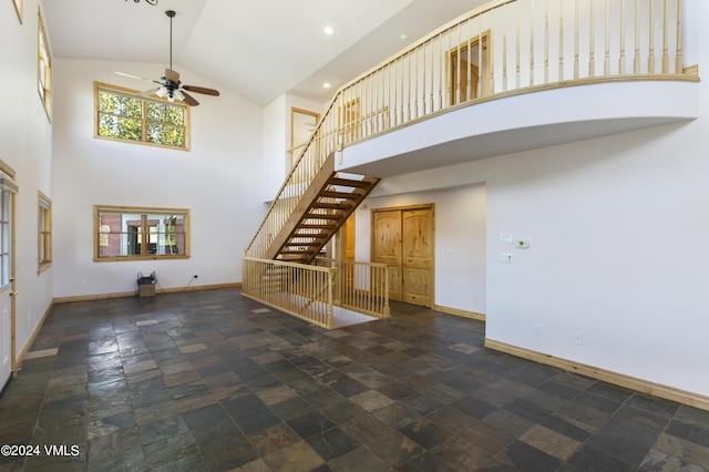 unfurnished living room featuring high vaulted ceiling and ceiling fan