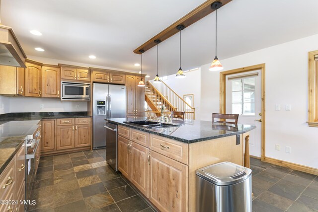 kitchen with pendant lighting, sink, stainless steel appliances, a center island, and dark stone counters