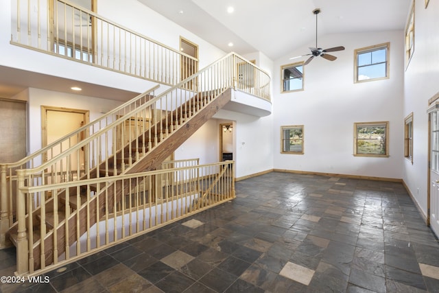 unfurnished living room with ceiling fan and a high ceiling