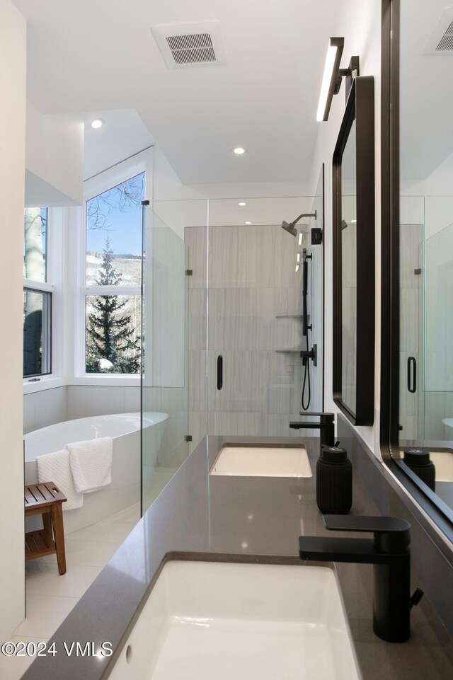 full bathroom featuring a freestanding tub, a shower stall, visible vents, and a sink