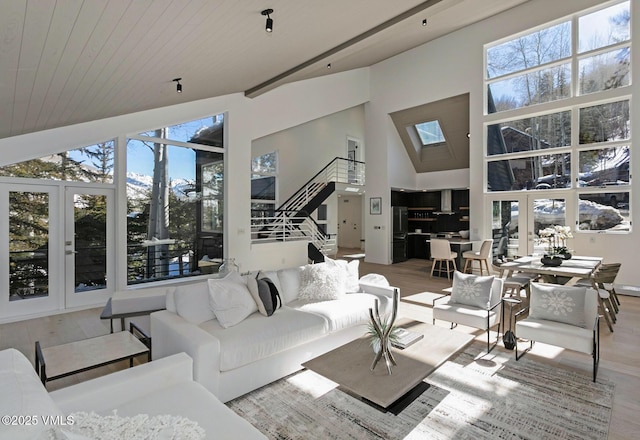 living area featuring a skylight, wooden ceiling, wood finished floors, stairs, and high vaulted ceiling