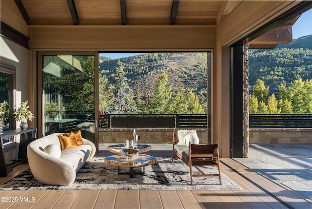 sunroom with a mountain view, lofted ceiling with beams, and wooden ceiling