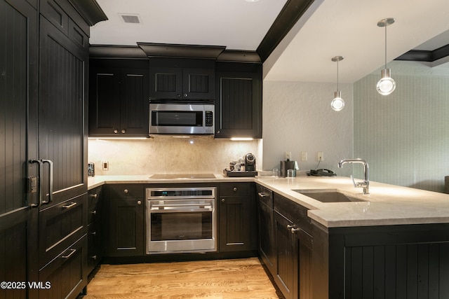 130 Daybreak Rdg Unit 732, Avon, CO 81620 - kitchen featuring appliances with stainless steel finishes, a sink, a peninsula, dark cabinetry, and light wood-style flooring
