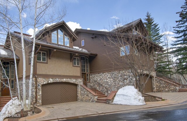 1120 Village Rd Unit 7, Beaver Creek, CO 81620 - chalet / cabin with stone siding, driveway, a garage, and stucco siding