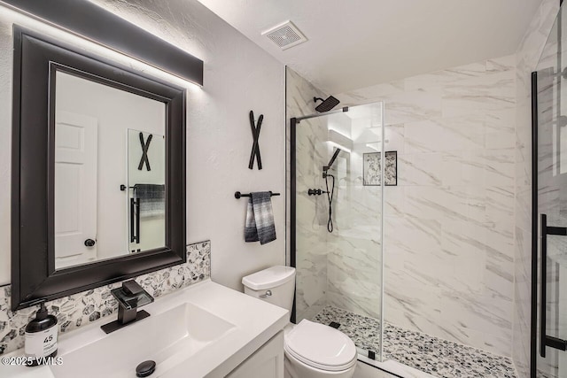 full bath with toilet, vanity, a marble finish shower, and visible vents