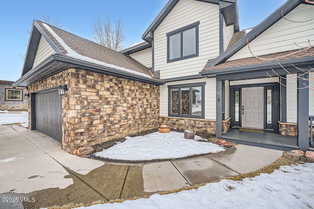 exterior space with an attached garage, stone siding, and a shingled roof