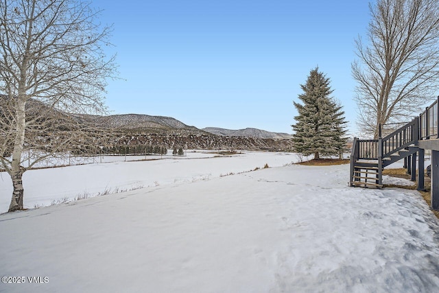 yard layered in snow featuring stairway and a mountain view