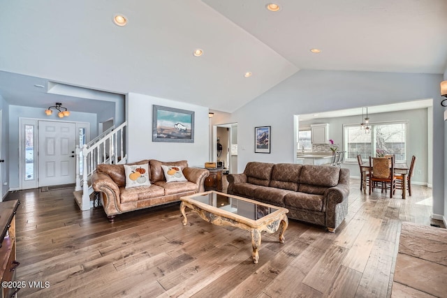 living room with recessed lighting, wood finished floors, baseboards, stairs, and vaulted ceiling