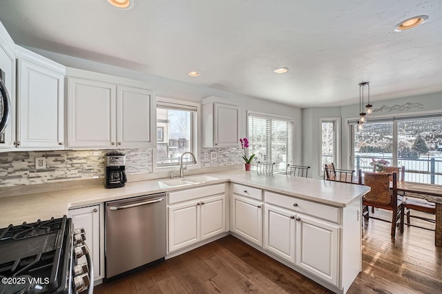 kitchen featuring stainless steel appliances, hanging light fixtures, light countertops, and white cabinets