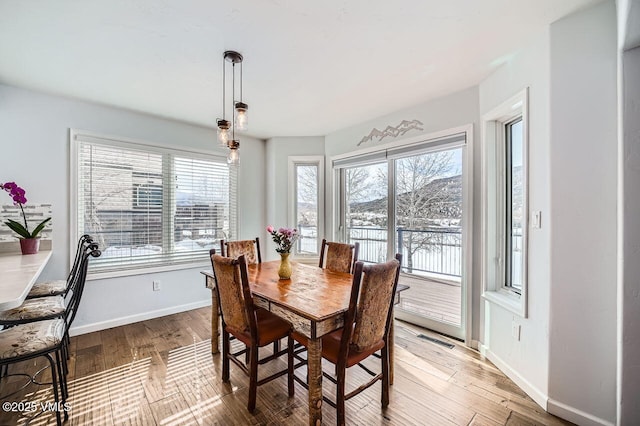 dining area with light wood-style floors, visible vents, and baseboards