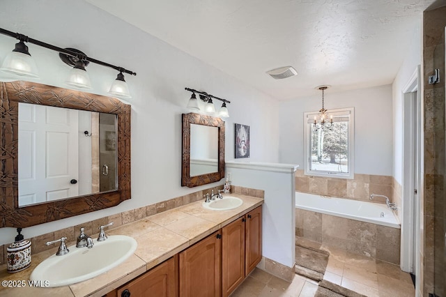 full bathroom featuring a garden tub, a sink, a notable chandelier, and double vanity