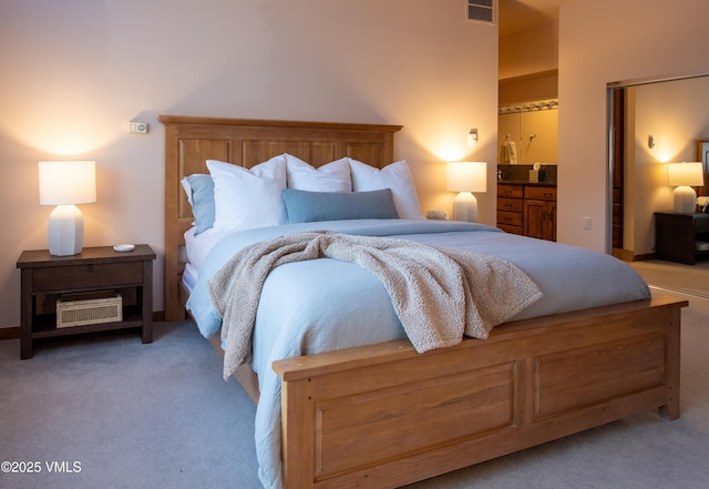 bedroom with ensuite bathroom and carpet floors