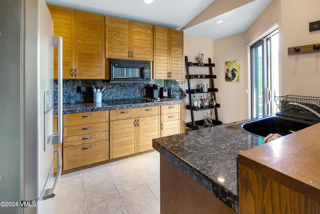 kitchen featuring tasteful backsplash, sink, light tile patterned floors, and black appliances