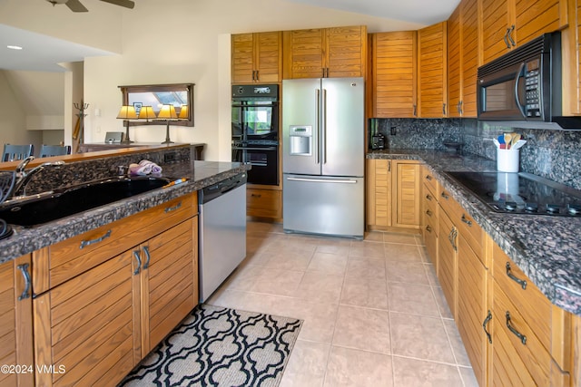 kitchen with light tile patterned flooring, sink, dark stone countertops, backsplash, and black appliances