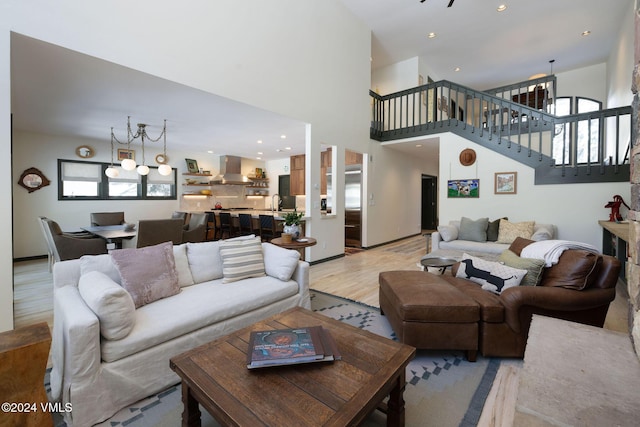 living room with a healthy amount of sunlight, a towering ceiling, sink, and light hardwood / wood-style floors