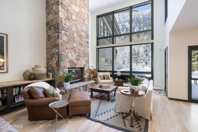 living room with a towering ceiling, a fireplace, and light hardwood / wood-style flooring