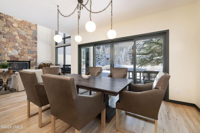 dining room featuring a stone fireplace and light hardwood / wood-style floors