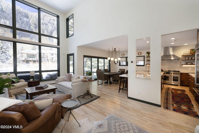 living room with a towering ceiling, an inviting chandelier, and light hardwood / wood-style flooring