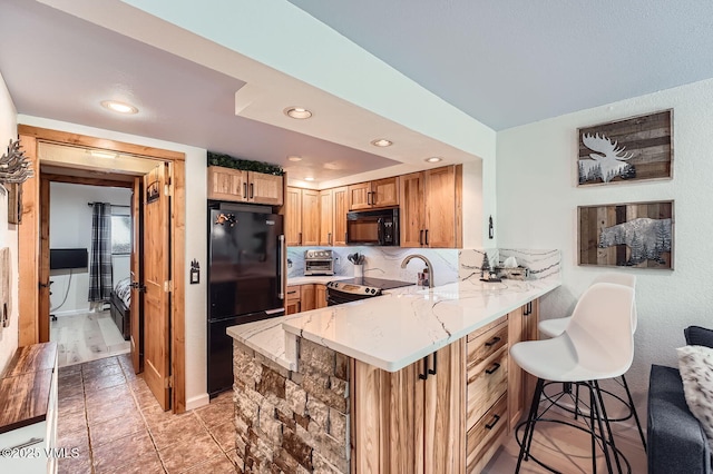 4570 Vail Racquet Club Dr Unit 2-3, Vail, CO 81657 - kitchen featuring black appliances, a peninsula, a kitchen bar, recessed lighting, and light stone countertops