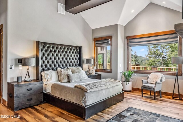 bedroom featuring high vaulted ceiling and light hardwood / wood-style flooring