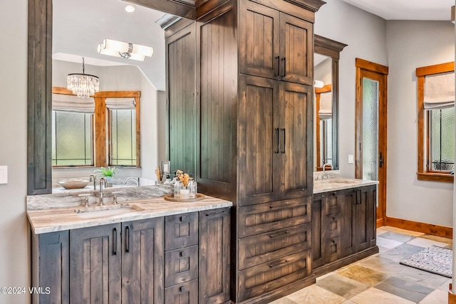 bathroom with an inviting chandelier, lofted ceiling, and vanity