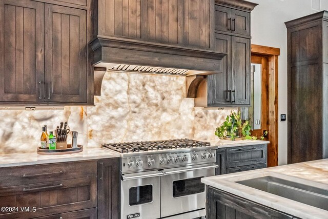 kitchen with double oven range, custom range hood, backsplash, and dark brown cabinetry