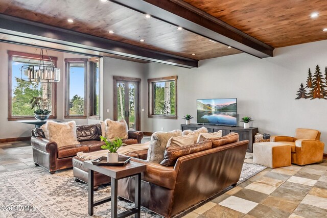 living room with an inviting chandelier, a wealth of natural light, beam ceiling, and wooden ceiling