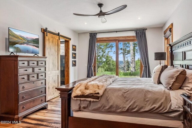 bedroom with ceiling fan, a barn door, access to exterior, and light wood-type flooring