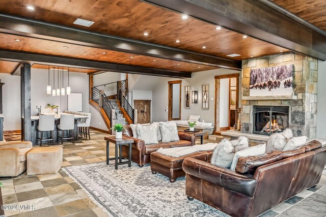 living room with wood ceiling, a stone fireplace, and beamed ceiling