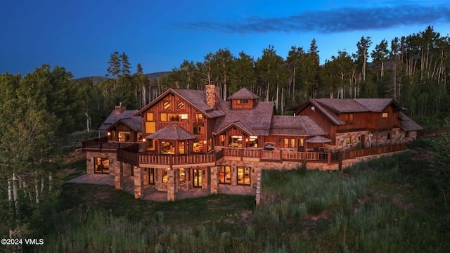 back house at dusk with a patio and a deck