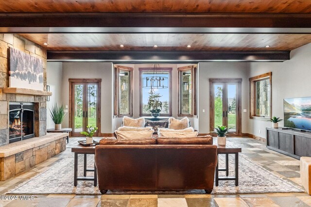 living room featuring beamed ceiling, a stone fireplace, and wooden ceiling