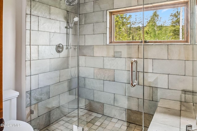 bathroom featuring a shower with door and toilet