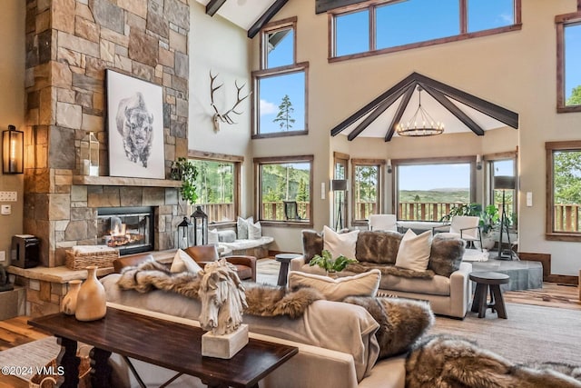 living room featuring a stone fireplace, high vaulted ceiling, beamed ceiling, a chandelier, and hardwood / wood-style flooring