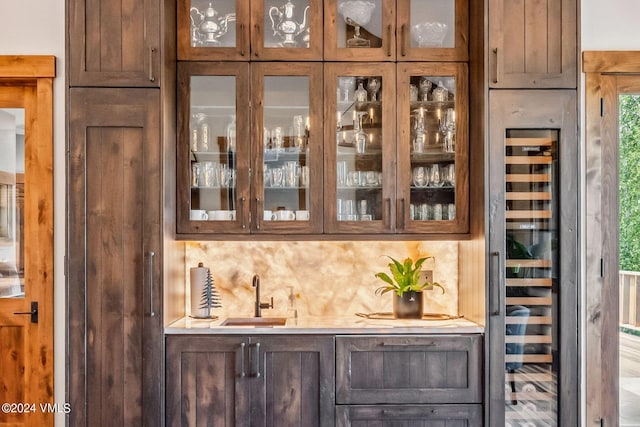 bar with beverage cooler, sink, and decorative backsplash