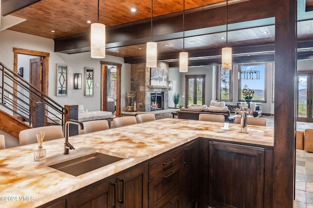 kitchen featuring dark brown cabinets, sink, a large fireplace, and decorative light fixtures