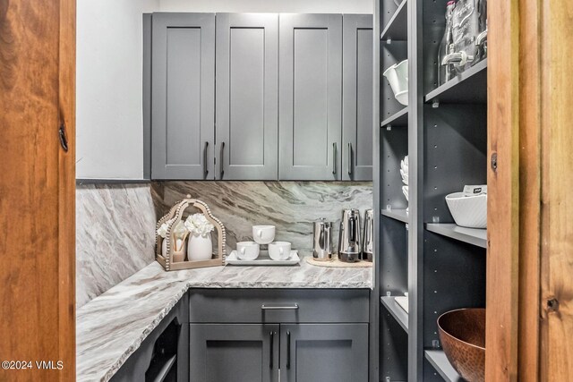 kitchen with gray cabinets, light stone countertops, and decorative backsplash