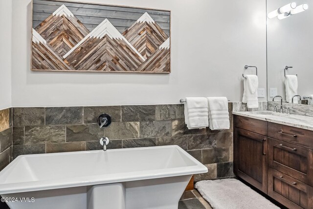 bathroom with vanity, a tub to relax in, and tile walls