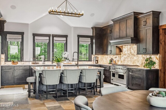 kitchen with extractor fan, sink, double oven range, a kitchen island with sink, and a notable chandelier