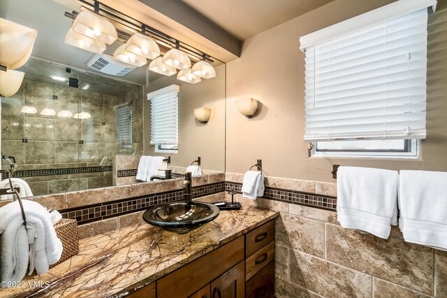 bathroom with vanity, tile walls, and walk in shower