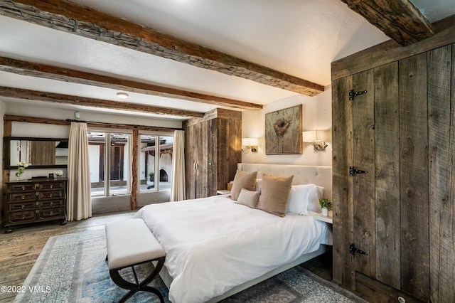 bedroom featuring beamed ceiling and access to exterior