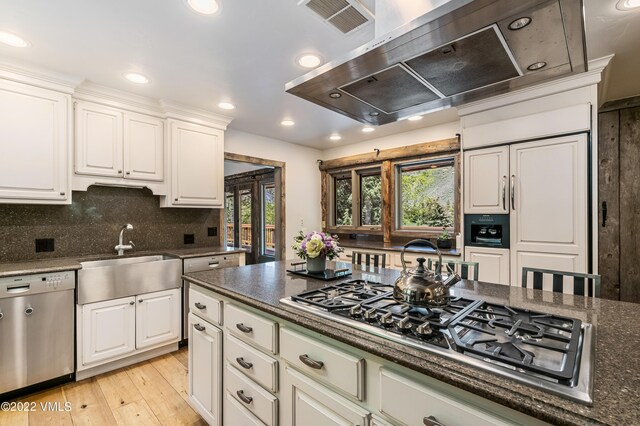 kitchen featuring white cabinetry, appliances with stainless steel finishes, sink, and wall chimney range hood