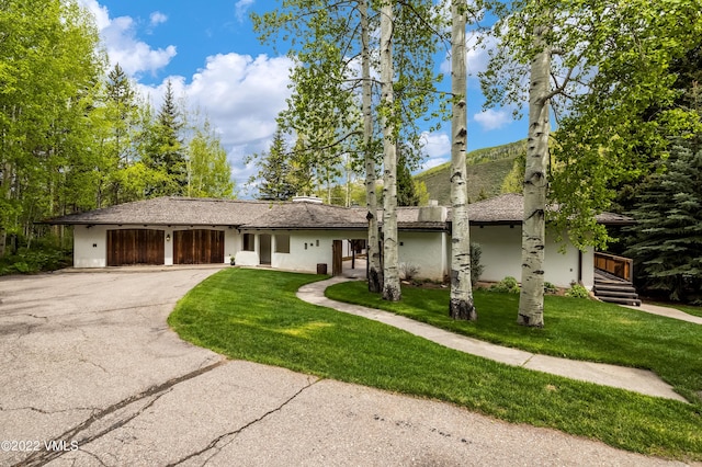 ranch-style home with a garage and a front lawn