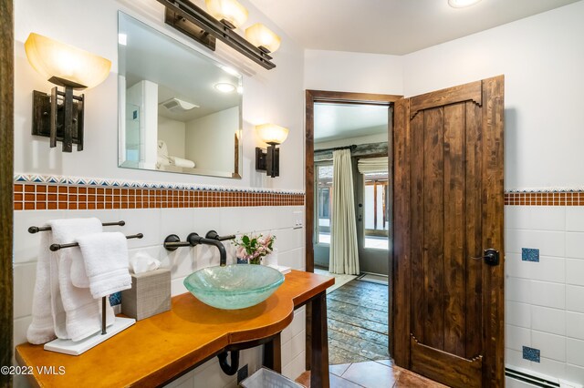 bathroom featuring tile walls, sink, tile patterned floors, and a baseboard heating unit