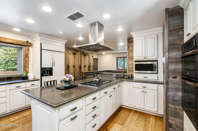 kitchen featuring stainless steel appliances, island range hood, white cabinets, and kitchen peninsula