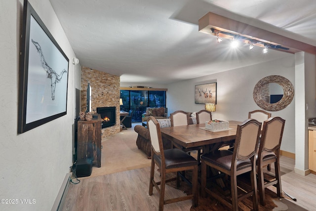 dining area with a stone fireplace and light hardwood / wood-style flooring